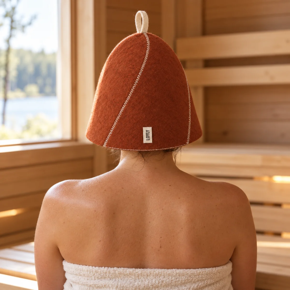 Pessoa vista de costas usando o gorro Pinhão de feltro de lã em uma sauna de madeira